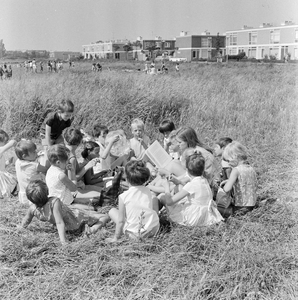 126545 Afbeelding van het voorlezen voor kinderen in het kader van vakantieontspanning op een veldje aan de Plutodreef ...